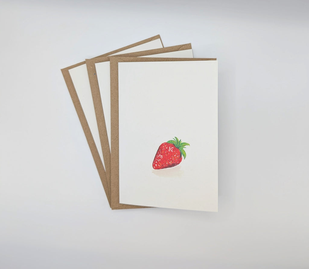 Hand-painted watercolour greeting card featuring a single plump strawberry, shown with kraft envelopes