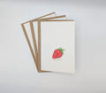 Hand-painted watercolour greeting card featuring a single plump strawberry, shown with kraft envelopes