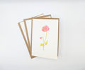 Hand-painted watercolour greeting card featuring a single pink bloom on a slender stem with a small bud, shown with kraft envelopes